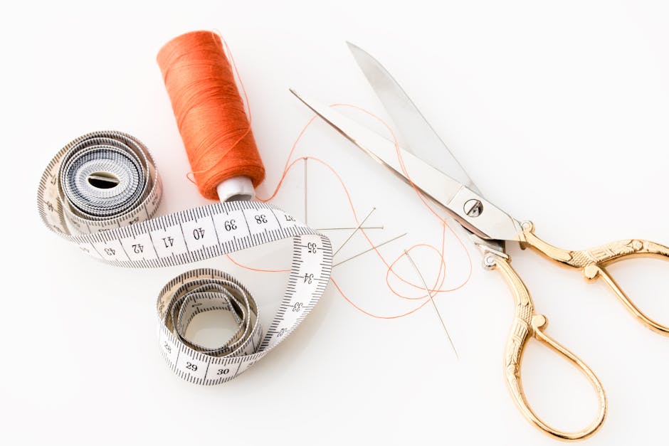 Photo of sewing essentials: scissors, thread, needles, and tape measure on a white background.