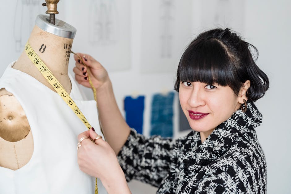 A fashion designer measures fabric on a mannequin in a studio setting, focused on crafting attire.